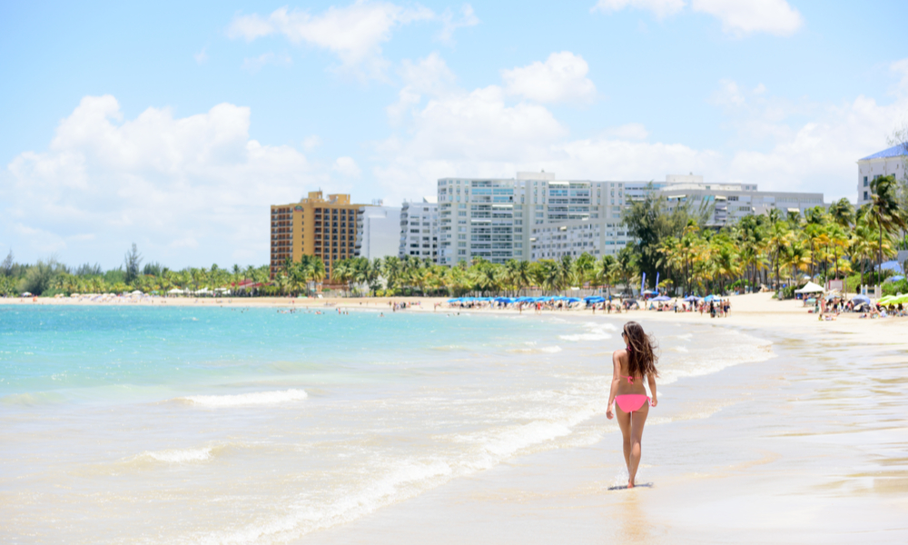 Unrecognizable woman walking down the beach on summer holiday in bikini on famous Hispanic travel destination.