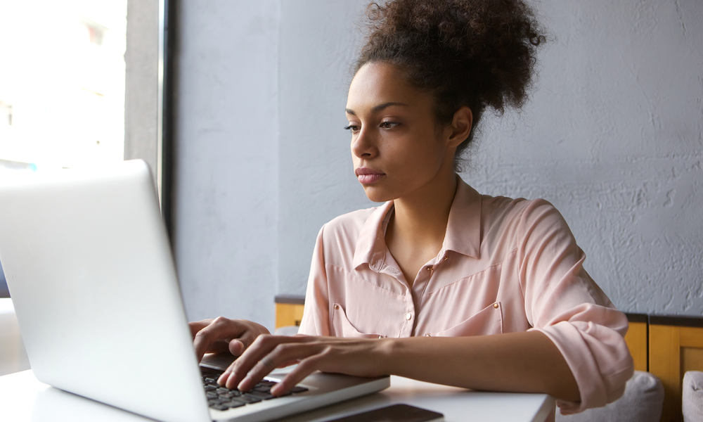 Close up portrait of a young woman working on laptop