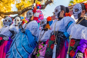 The Best Places to Celebrate Day of the Dead in the US: Group of unrecognizable women wearing traditional sugar skull masks and costumes for Dia de los Muertos celebration