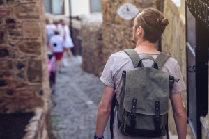 How to stay safe abroad: Man traveler with backpack explore the village walking on the old streets and explore the castles and fortresses.