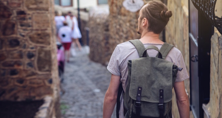 How to stay safe abroad: Man traveler with backpack explore the village walking on the old streets and explore the castles and fortresses.