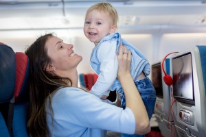 How to prepare for flying with a toddler: Mother, entertaining little toddler boy on board of aircraft on a long distance international flight, while traveling to a holiday