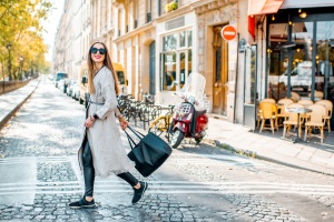 How to do Paris on a budget: Street view with traditional french cafe and woman walking during the morning in Paris