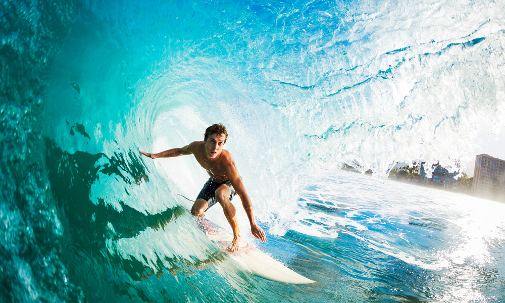 The Best Places to Surf in Hawaii in the Winter Season: Surfer on Blue Ocean Wave in the Tube Getting Barreled