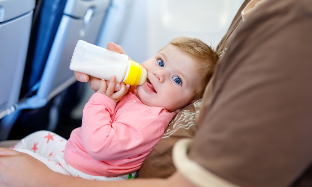  What you need to know when flying with a baby: Father holding baby daughter during flight on airplane