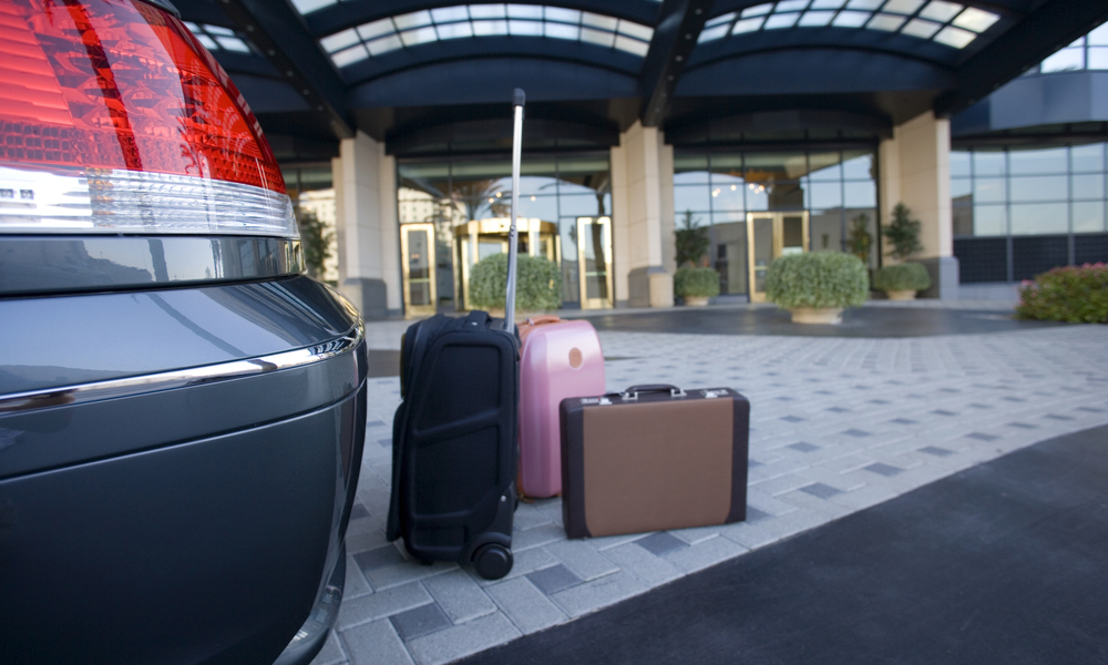 tips for and alternatives to parking at the airport: Luggage beside parked car outside hotel