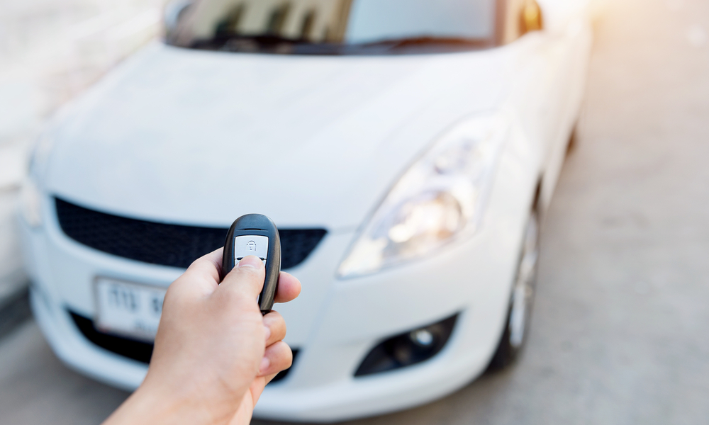 tips for and alternatives to parking at the airport: Hand holding car's remote control.