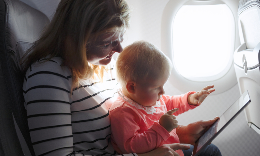 What you need to know when flying with a baby: Mom and child playing tablet while flying on plane