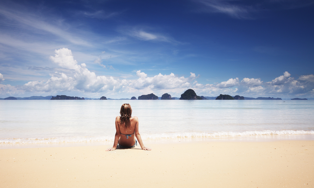 how to travel cheap: woman on a lonely beach during off-season