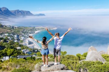 Couple with hands up at The Rock viewpoint in Cape Town Campsbay