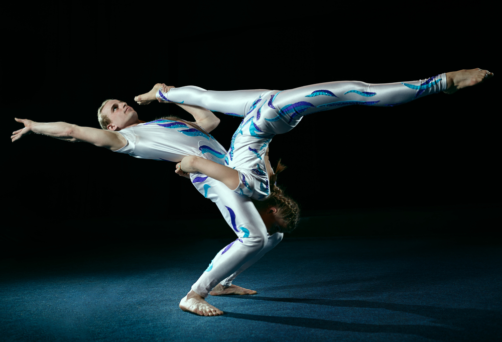 Circus artists perform different tricks. Gym split.