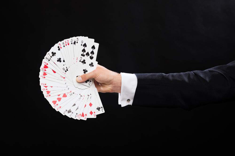 magic, performance, circus, gambling, casino, poker, show concept - close up of magician hand holding playing cards