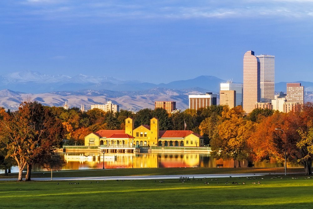 Denver Colorado skyline from City Park with City Park Boathouse and Rocky Mountains in background on autumn morning