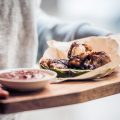 Fried buffalo chicken wings on wooden board. Toned image