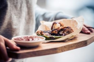 Fried buffalo chicken wings on wooden board. Toned image