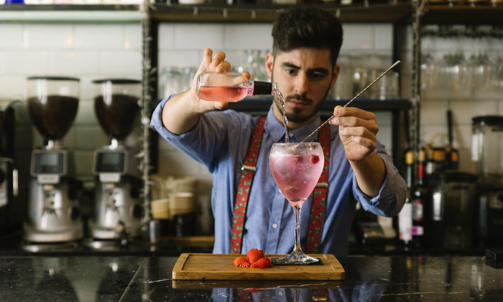 Expert barman is making cocktail at night club.