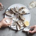 Delicious oysters with slice of lemon and glasses of white wine, top view