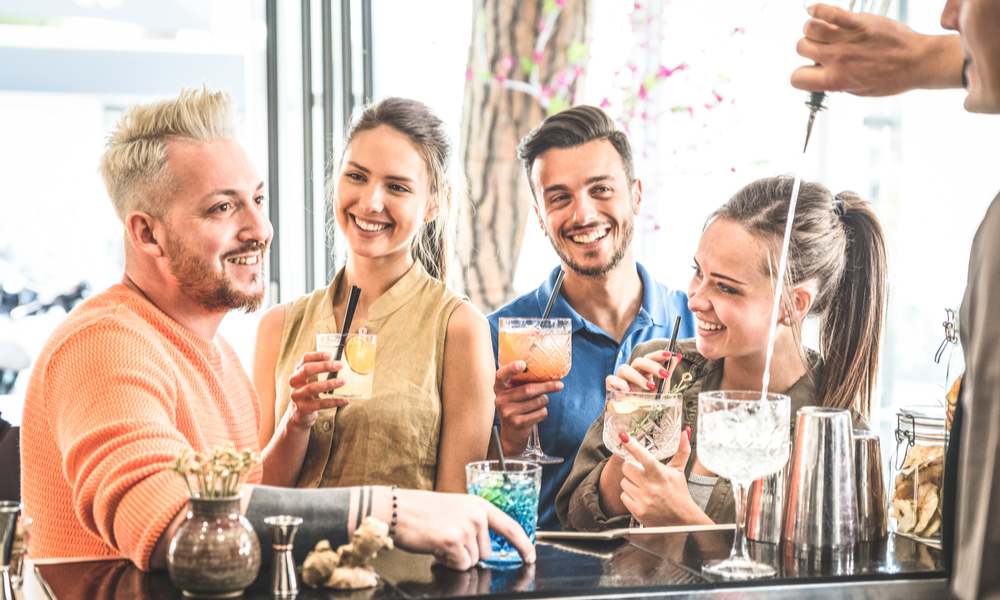 Group of friends drinking cocktails and talking at restaurant