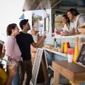 Smiling waiter taking order from couple at counter