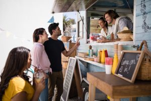 Smiling waiter taking order from couple at counter