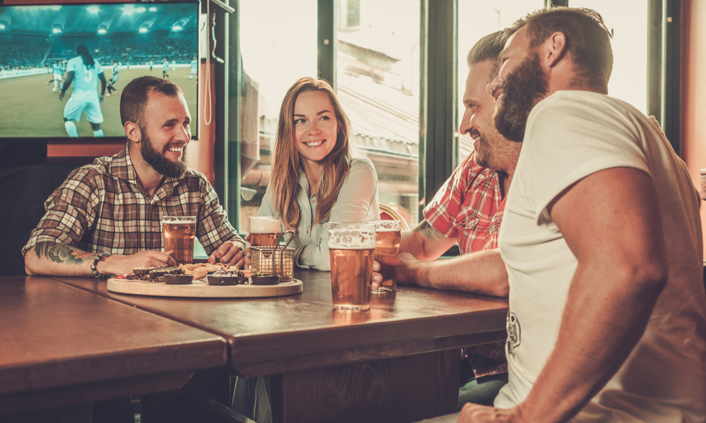 Friends drinking beer and watching soccer in a pub