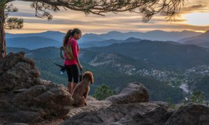 Exciting & adventurous things to do in denver: A hispanic woman is hiking with a dog, in the Rocky Mountains, of Colorado.